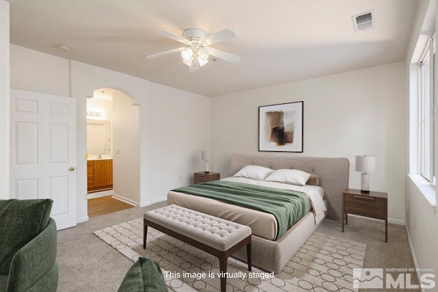 bedroom featuring visible vents, arched walkways, carpet flooring, baseboards, and ceiling fan