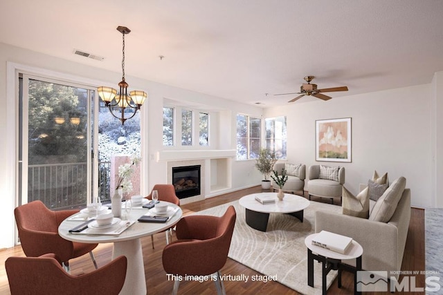 interior space with visible vents, ceiling fan with notable chandelier, wood finished floors, and a tile fireplace