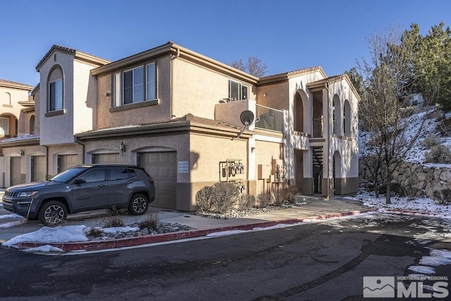 view of property with stucco siding, driveway, and a garage