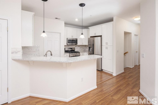 kitchen with stainless steel appliances, kitchen peninsula, light hardwood / wood-style floors, and white cabinets