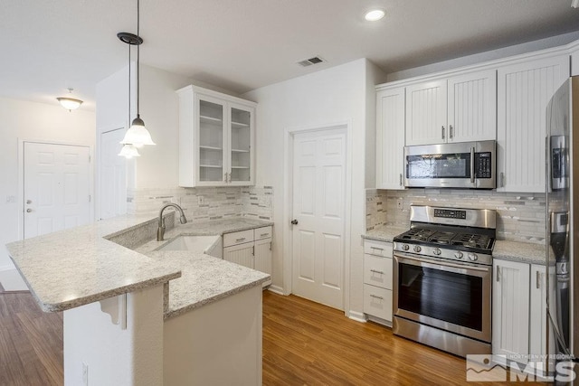 kitchen featuring sink, white cabinetry, hanging light fixtures, kitchen peninsula, and stainless steel appliances