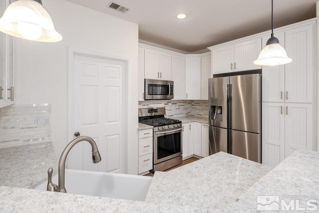 kitchen featuring hanging light fixtures, stainless steel appliances, sink, and white cabinets