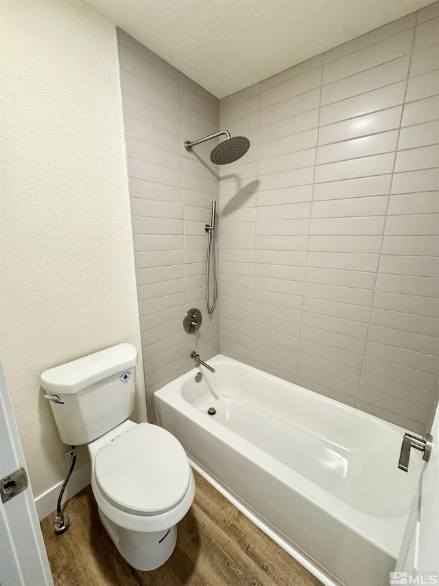 bathroom featuring hardwood / wood-style flooring, tiled shower / bath combo, a textured ceiling, and toilet