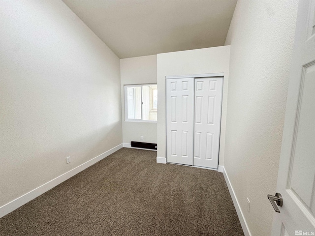 unfurnished bedroom featuring vaulted ceiling, a closet, and dark colored carpet