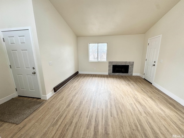 unfurnished living room featuring lofted ceiling, a high end fireplace, baseboard heating, and light hardwood / wood-style flooring