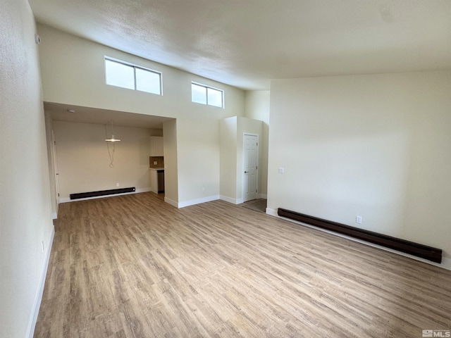 unfurnished living room featuring a baseboard heating unit and light hardwood / wood-style flooring