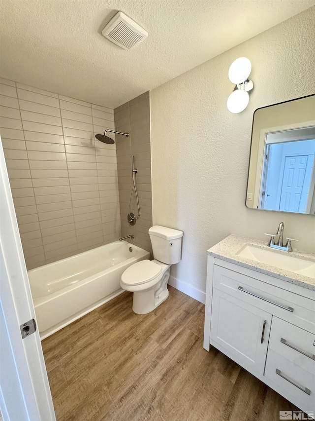 full bathroom featuring hardwood / wood-style flooring, vanity, a textured ceiling, toilet, and tiled shower / bath