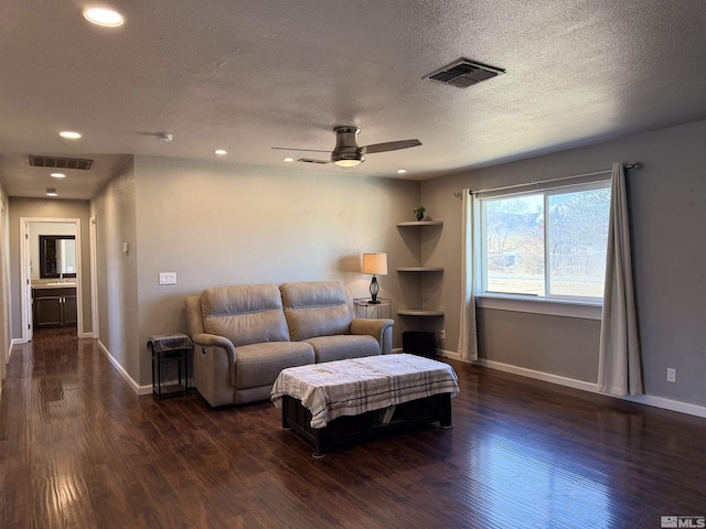 living room featuring ceiling fan, dark hardwood / wood-style flooring, and a textured ceiling