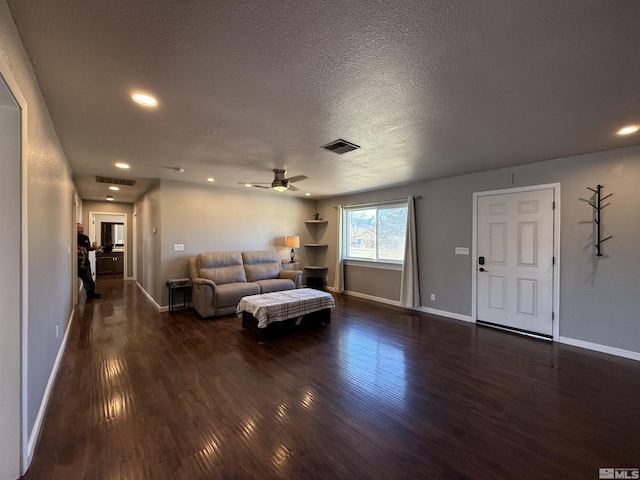 living room with ceiling fan, dark hardwood / wood-style floors, and a textured ceiling