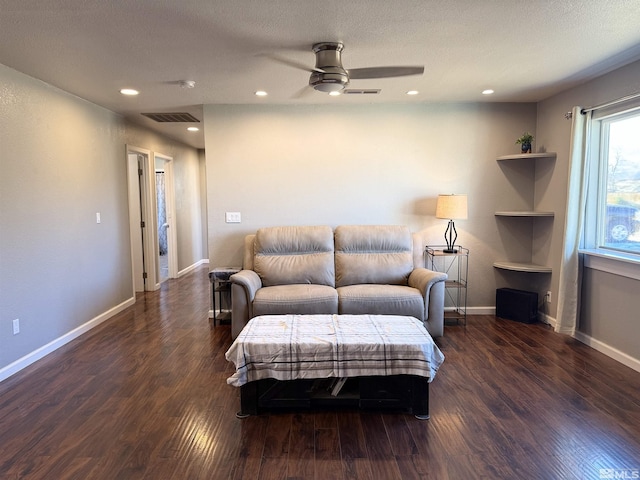 living room with ceiling fan, dark hardwood / wood-style flooring, and a textured ceiling