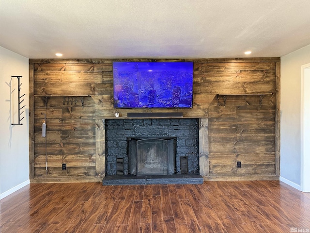 unfurnished living room featuring a stone fireplace and dark wood-type flooring