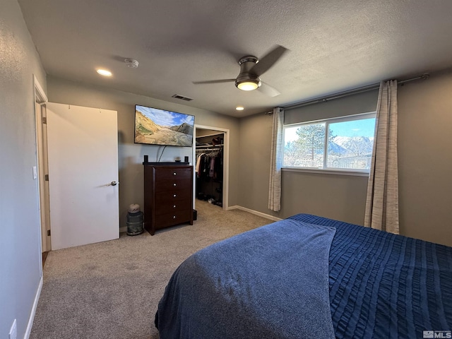 carpeted bedroom featuring ceiling fan, a spacious closet, and a textured ceiling