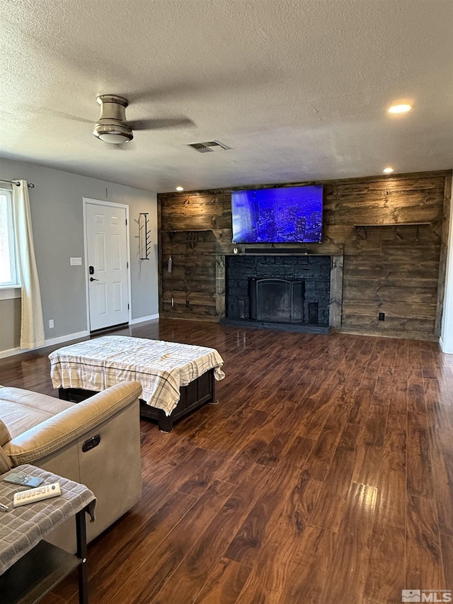 living room with a fireplace, dark wood-type flooring, and a textured ceiling