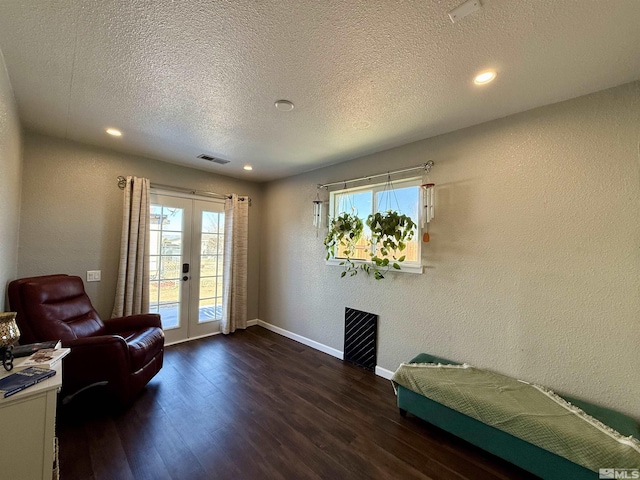 sitting room with a healthy amount of sunlight, a textured ceiling, dark hardwood / wood-style flooring, and french doors