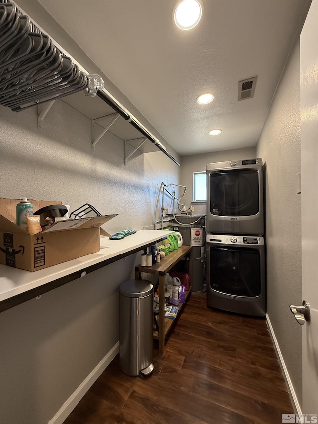 laundry room featuring stacked washer / drying machine, a textured ceiling, and dark hardwood / wood-style flooring