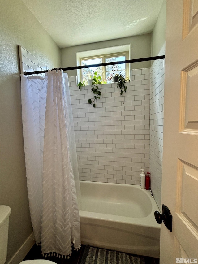 bathroom with shower / tub combo, toilet, and a textured ceiling