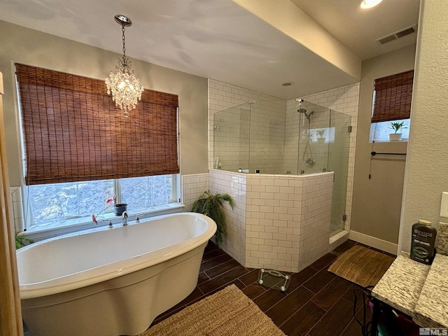 bathroom with an inviting chandelier and shower with separate bathtub