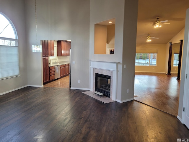 unfurnished living room with sink, ceiling fan, hardwood / wood-style floors, high vaulted ceiling, and a fireplace