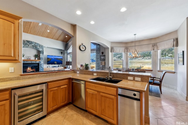 kitchen featuring wine cooler, sink, decorative light fixtures, kitchen peninsula, and a healthy amount of sunlight