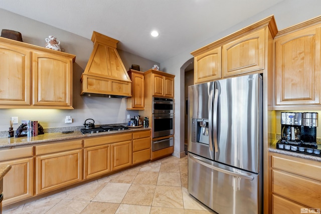 kitchen with light stone counters, premium range hood, and appliances with stainless steel finishes