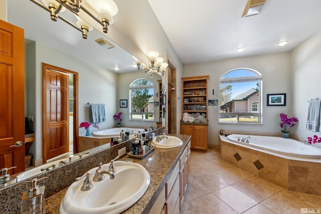 bathroom with an inviting chandelier, vanity, tile patterned flooring, and tiled tub