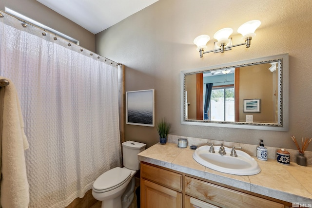 bathroom with walk in shower, ceiling fan, vanity, and toilet