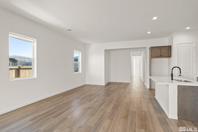 unfurnished living room featuring sink and light hardwood / wood-style flooring