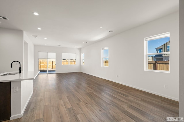 unfurnished living room featuring sink and hardwood / wood-style flooring