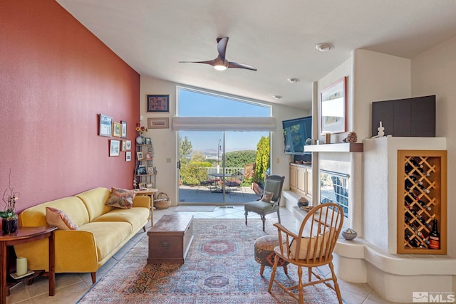 living room featuring lofted ceiling, light tile patterned floors, a fireplace, and ceiling fan