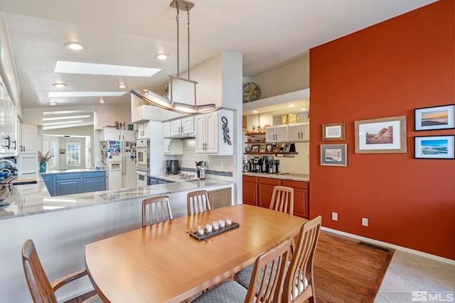 dining room with sink, light tile patterned floors, and a skylight