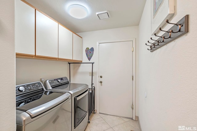 laundry room with cabinets, light tile patterned flooring, and separate washer and dryer