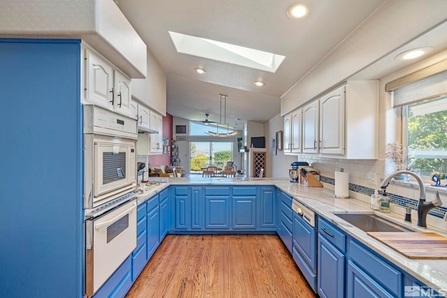 kitchen with blue cabinets, white cabinetry, sink, decorative backsplash, and kitchen peninsula