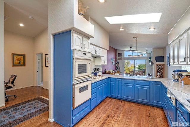 kitchen with blue cabinets, decorative light fixtures, white cabinets, and kitchen peninsula