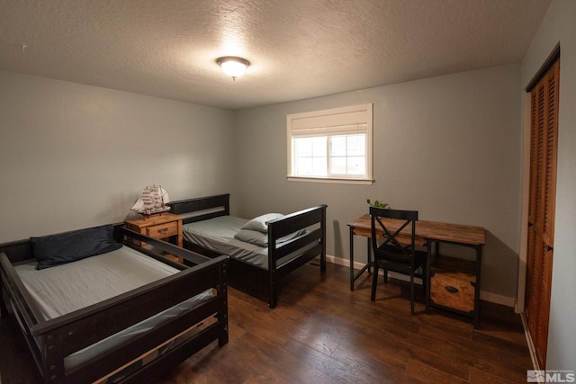 bedroom featuring a closet, dark hardwood / wood-style floors, and a textured ceiling