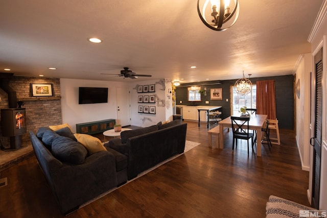 living room featuring ceiling fan with notable chandelier, dark hardwood / wood-style floors, and a wood stove