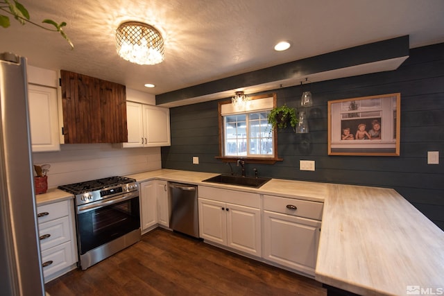 kitchen with sink, an inviting chandelier, dark hardwood / wood-style flooring, stainless steel appliances, and white cabinets