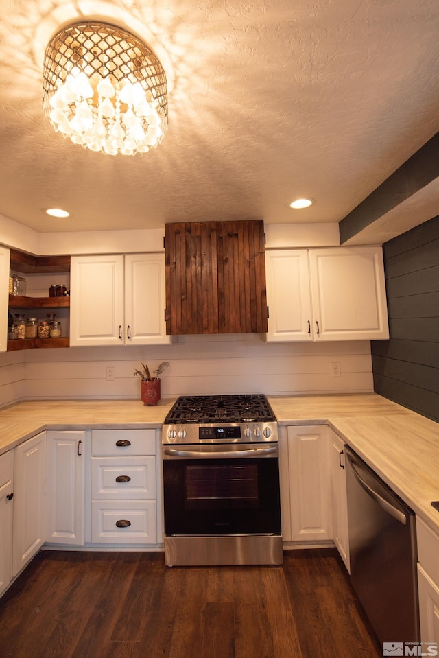 kitchen with dark wood-type flooring, white cabinetry, an inviting chandelier, stainless steel appliances, and a textured ceiling