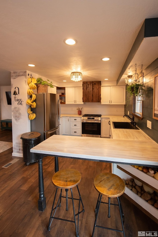 kitchen with sink, a kitchen bar, white cabinets, and appliances with stainless steel finishes