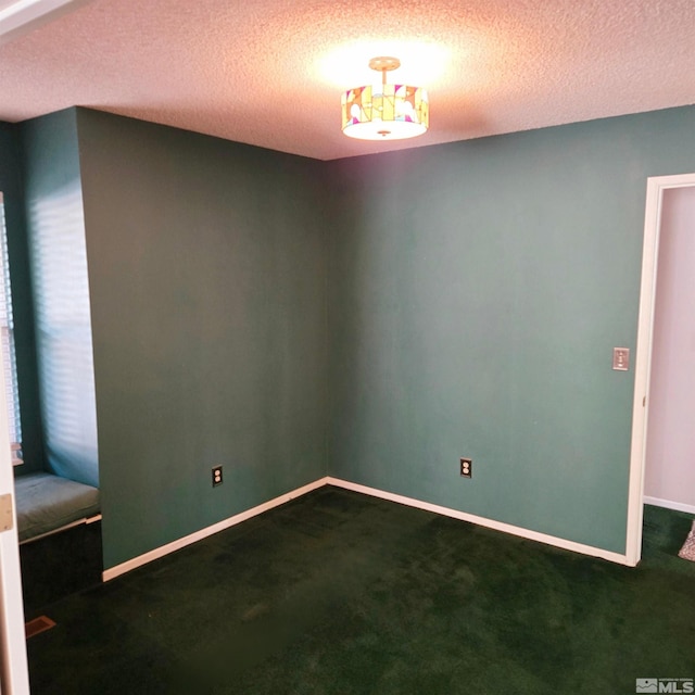 empty room with dark carpet and a textured ceiling