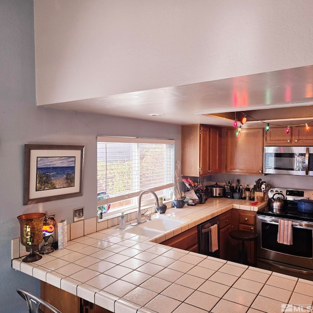 kitchen featuring sink, tile countertops, and stainless steel appliances