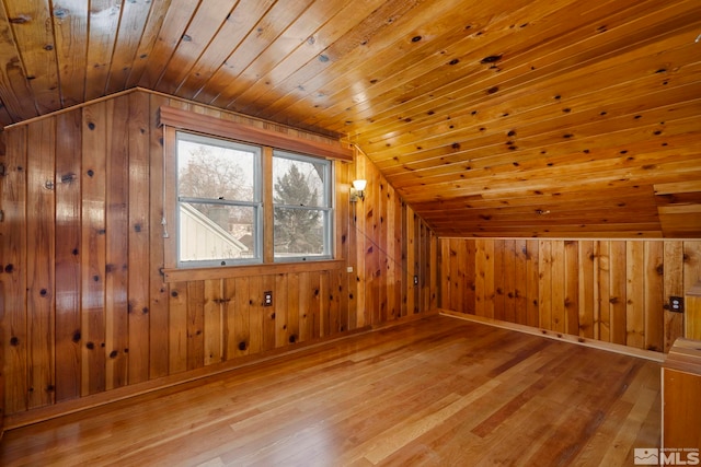 bonus room with lofted ceiling, light hardwood / wood-style flooring, wooden ceiling, and wooden walls