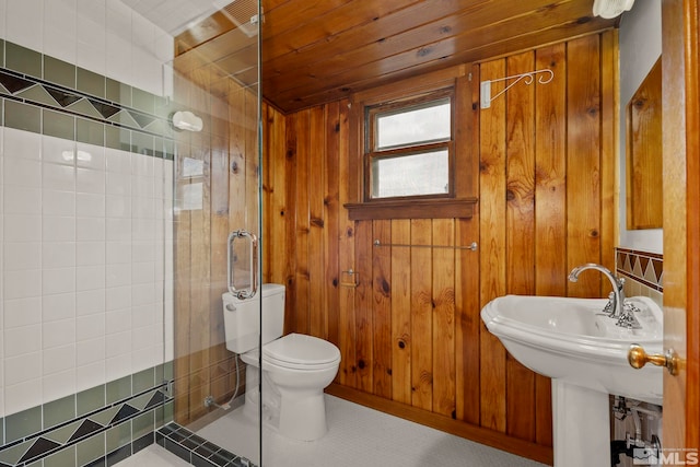 bathroom with a tile shower, wood ceiling, wooden walls, and toilet