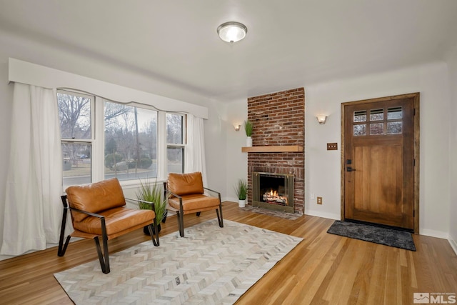 living area with a brick fireplace and light wood-type flooring