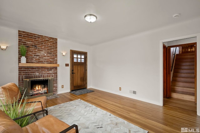 living room with a brick fireplace and hardwood / wood-style flooring