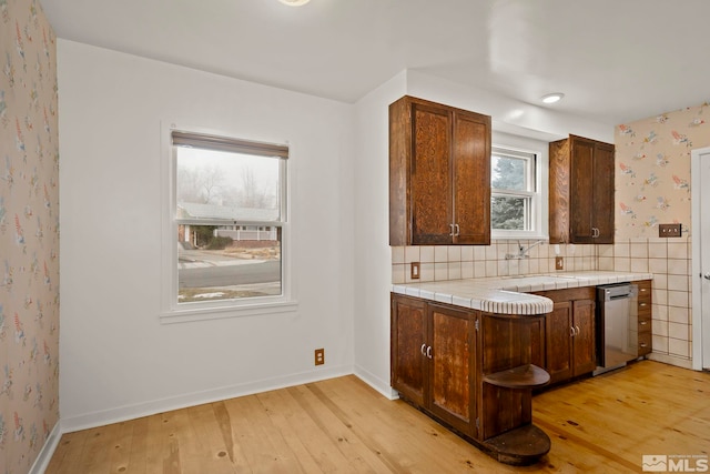 kitchen featuring sink, tile countertops, stainless steel dishwasher, and light hardwood / wood-style floors