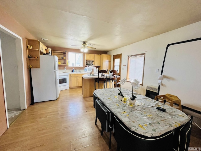 kitchen with light brown cabinetry, heating unit, a kitchen island, white appliances, and light hardwood / wood-style floors