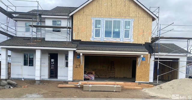 unfinished property featuring a garage and a shingled roof