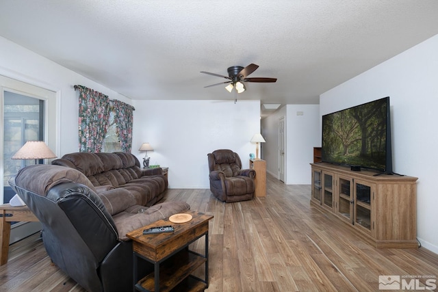 living room featuring ceiling fan, hardwood / wood-style flooring, and a textured ceiling