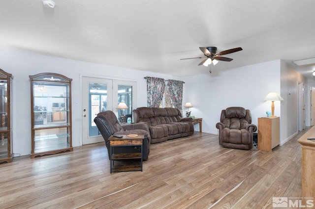 living room featuring ceiling fan, a textured ceiling, light wood-type flooring, and french doors