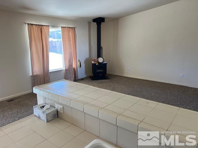 interior space with light colored carpet and a wood stove